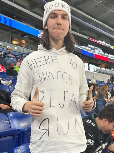 Fan with a white hoodie and hat at a sports event.