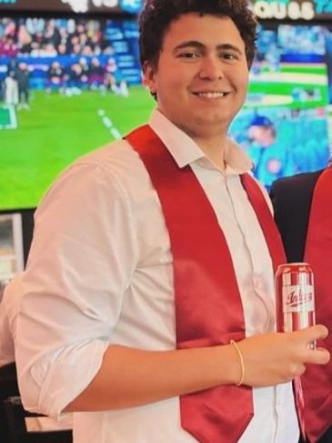 Young man in white shirt and red sash holding a can.