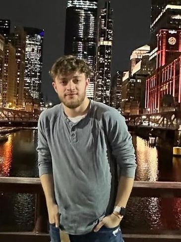 Young man posing by a river at night in the city.