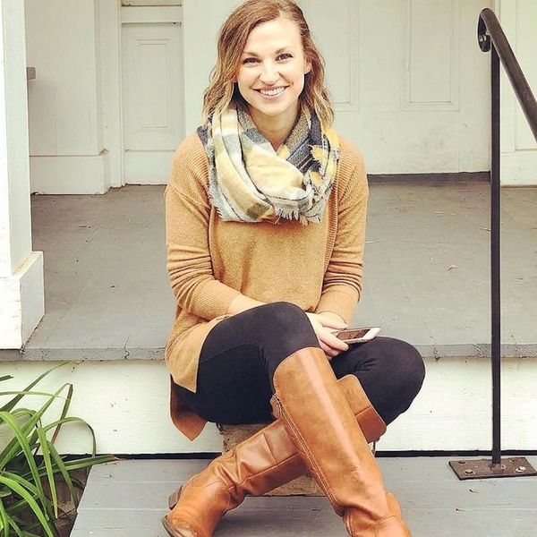 Smiling woman sitting on porch steps wearing a scarf and boots.