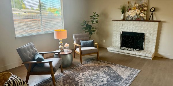Cozy living room with two armchairs by a fireplace and a decorative rug.