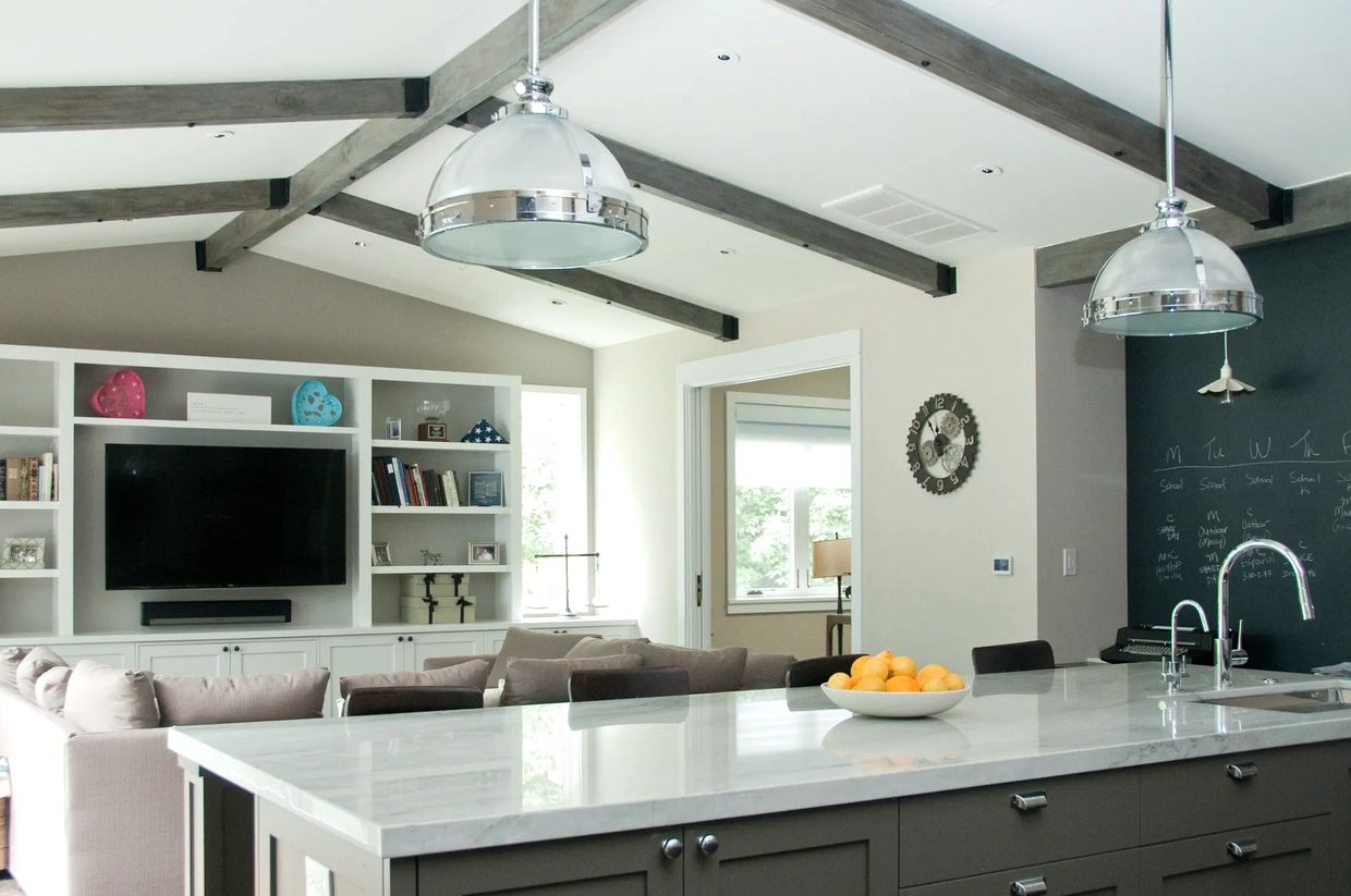 Modern kitchen island with a bowl of oranges and living room in the background.