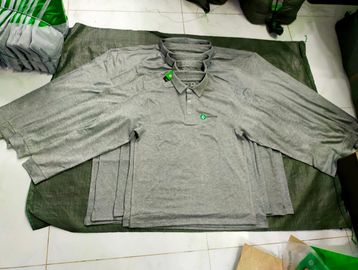 Stack of gray polo shirts laid out on a surface.