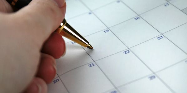Hand holding a pen over a calendar.