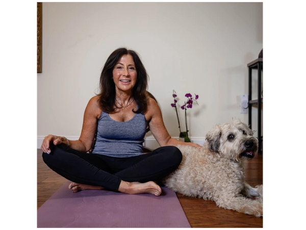 Woman in workout clothes sitting cross-legged on a yoga mat