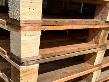 Pilas de tarimas de madera apiladas al aire libre.