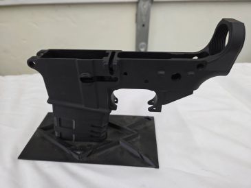 Black firearm lower receiver on a display stand.