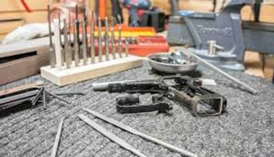 Disassembled firearm components and tools on a workbench.