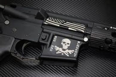 Close-up of a black firearm with a skull and crossed rifles design.