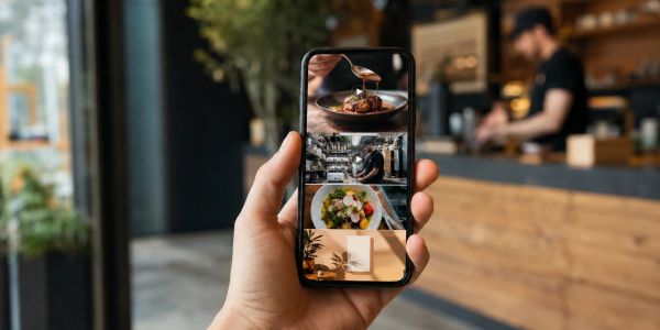 Person holding phone showing food and restaurant images.