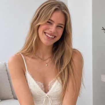 Smiling young woman with long blonde hair in a white dress.