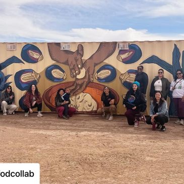 Group of people posing in front of a colorful mural depicting hands and food items.