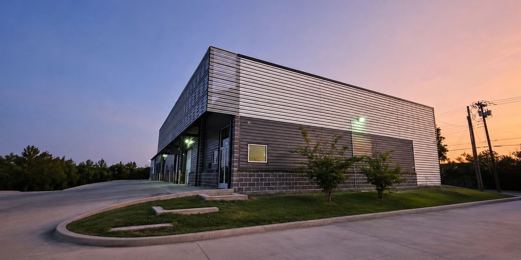 Warehouse building during sunset with surrounding greenery.