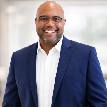 Smiling man in glasses wearing a blue suit and white shirt.