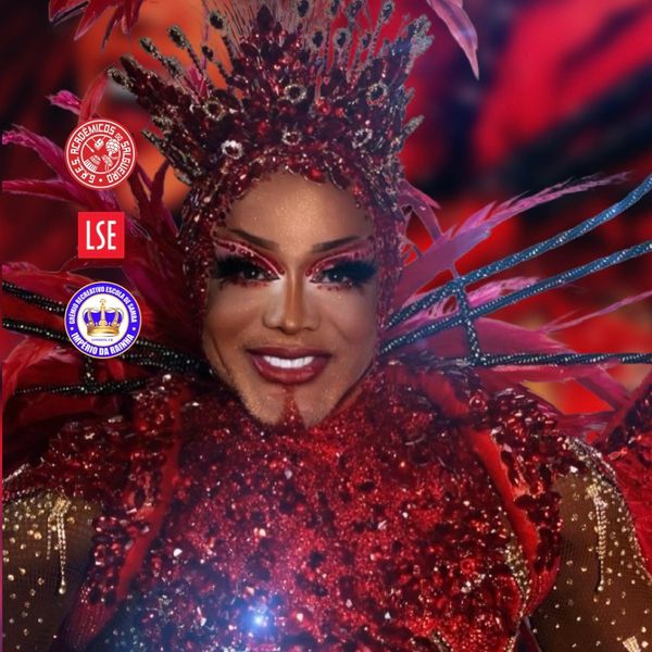Person in an elaborate red costume with intricate headpiece and makeup.