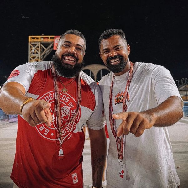 Two men smiling and pointing at the camera during a nighttime event.