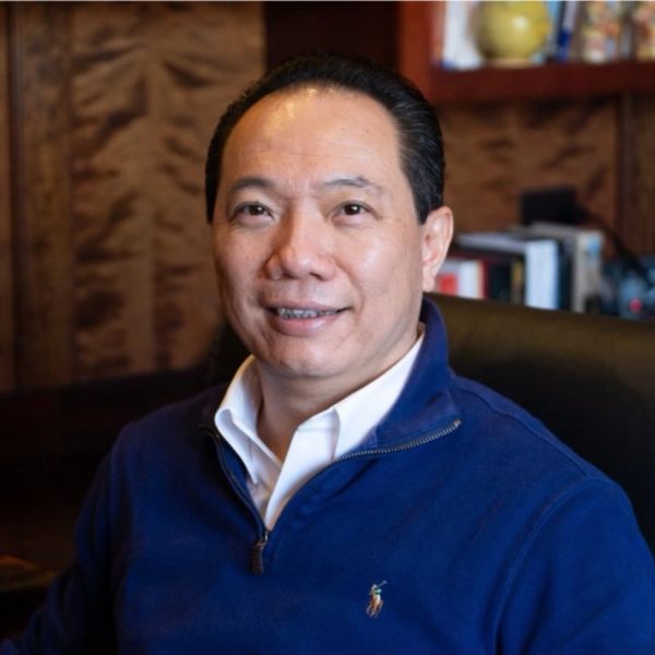 Smiling man in a blue sweater sitting in an office setting.