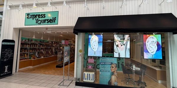 Storefront of Express Yourself with colorful ear art displays.