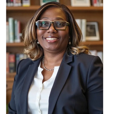 Professional woman in glasses and blazer smiling in a library setting.