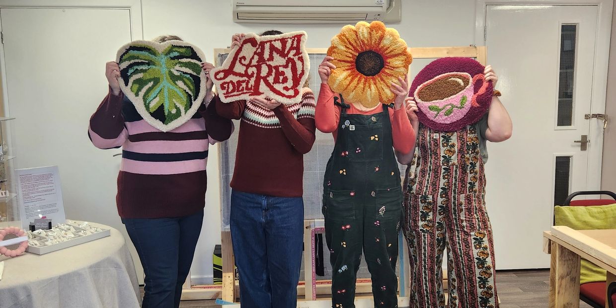 Group of people holding handmade rugs, a teacup, leaf and flower rug