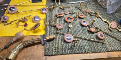 Parts of saxophone keys and rods laid out on a workbench for repair or assembly.