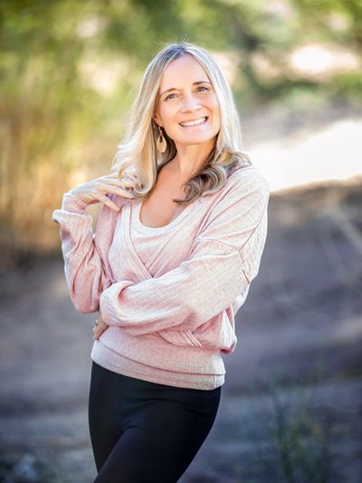 Young, blonde-haired woman smiling on a sunny day.