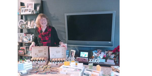 woman standing behind product table of soap and essential oils.