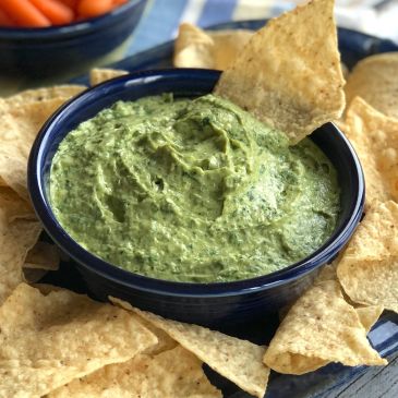 Bowl of creamy spinach dip with tortilla chips.