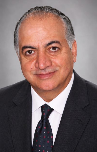 Middle-aged man in a suit and tie smiling.