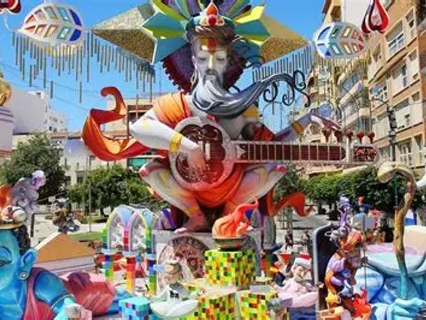 Colorful festival sculpture of a bearded figure playing a stringed instrument outdoors.