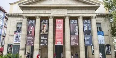 Historic building with large columns and banners in a city street.