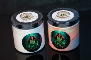 Two decorative mermaid candles in jars with black lids.