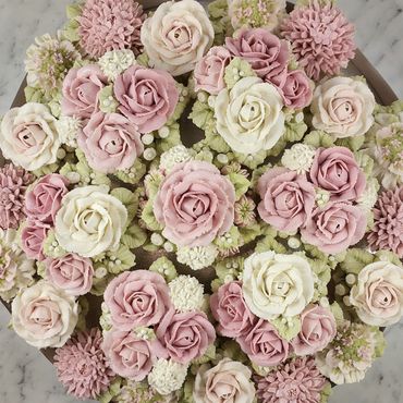 A beautiful arrangement of pink and white buttercream flowers on a cake.