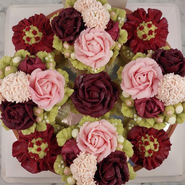 A beautifully decorated cake with intricate pink, burgundy, and cream floral designs.