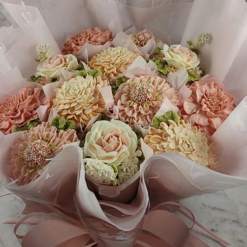 Elegant pastel flower bouquet wrapped in translucent pink paper with a matching bow.