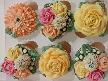 Cupcakes decorated with intricate buttercream flowers in pastel colors.