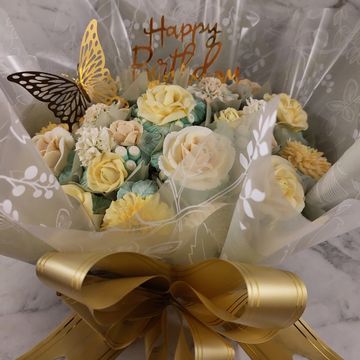 Elegant birthday bouquet with pastel flowers and a golden butterfly accent.