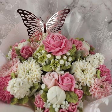 A bouquet of pink and white flowers with a metallic butterfly decoration.