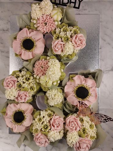 Cupcakes decorated with pastel flowers on a silver tray.
