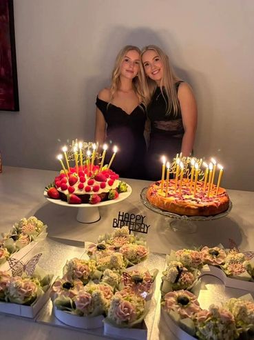 Two women celebrating a birthday with cakes and flower decorations.