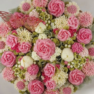 A colorful bouquet of intricately crafted pink and white flowers with a decorative butterfly.