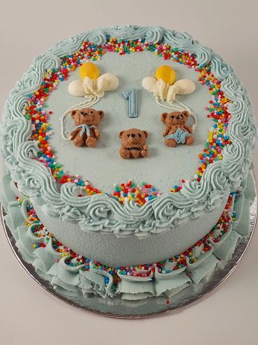 Blue frosted cake with teddy bears and number 1 decoration.