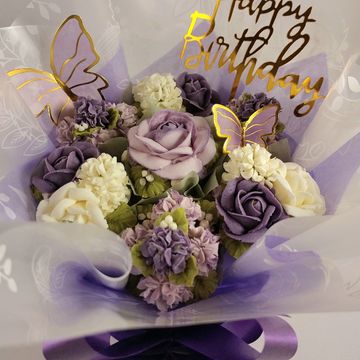 Elegant purple and white flower bouquet with Happy Birthday sign and butterfly decorations.