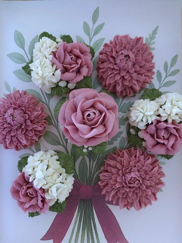 A bouquet of pink and white buttercream flowers on a leafy background.