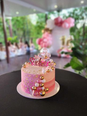 Elegant pink and gold sixteenth birthday cake with decorative bubbles and butterflies.