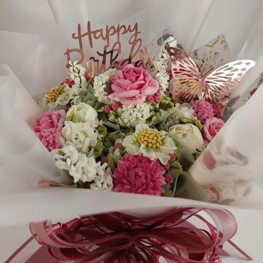 Elegant birthday bouquet with pink and white flowers and a decorative butterfly.