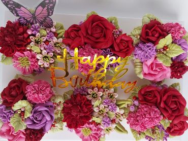Colorful birthday floral arrangement with a golden 'Happy Birthday' sign and a butterfly.
