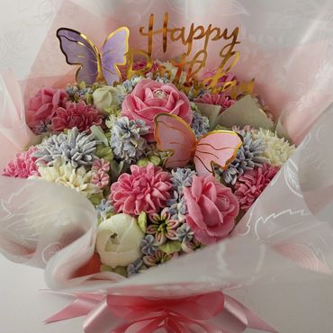 A beautiful bouquet of pastel flowers with butterfly decorations and a Happy Birthday sign.