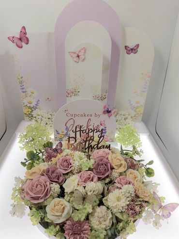Elegant floral birthday cupcake arrangement with pastel butterflies.