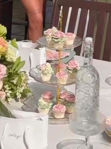 Tiered stand with decorated cupcakes on a white table at an event.